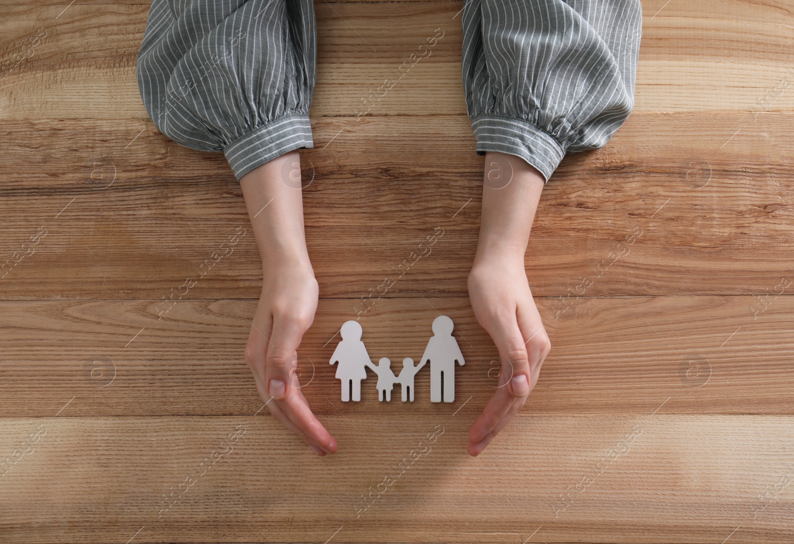 Photo of Woman with figure of family at wooden table, top view