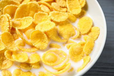 Photo of Tasty crispy corn flakes with milk in bowl, closeup