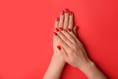 Photo of Woman with gel polish on nails against red background, closeup. Space for text