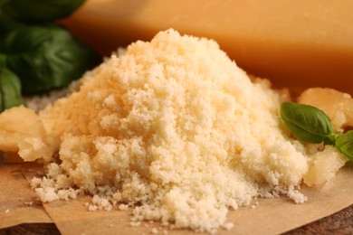 Photo of Delicious grated parmesan cheese and basil on parchment paper, closeup