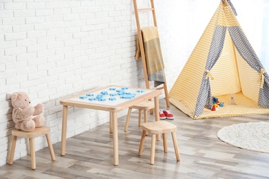 Photo of Cozy kids room interior with table, stools and play tent
