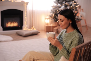 Photo of Young woman with cup of hot drink at home, space for text. Christmas celebration