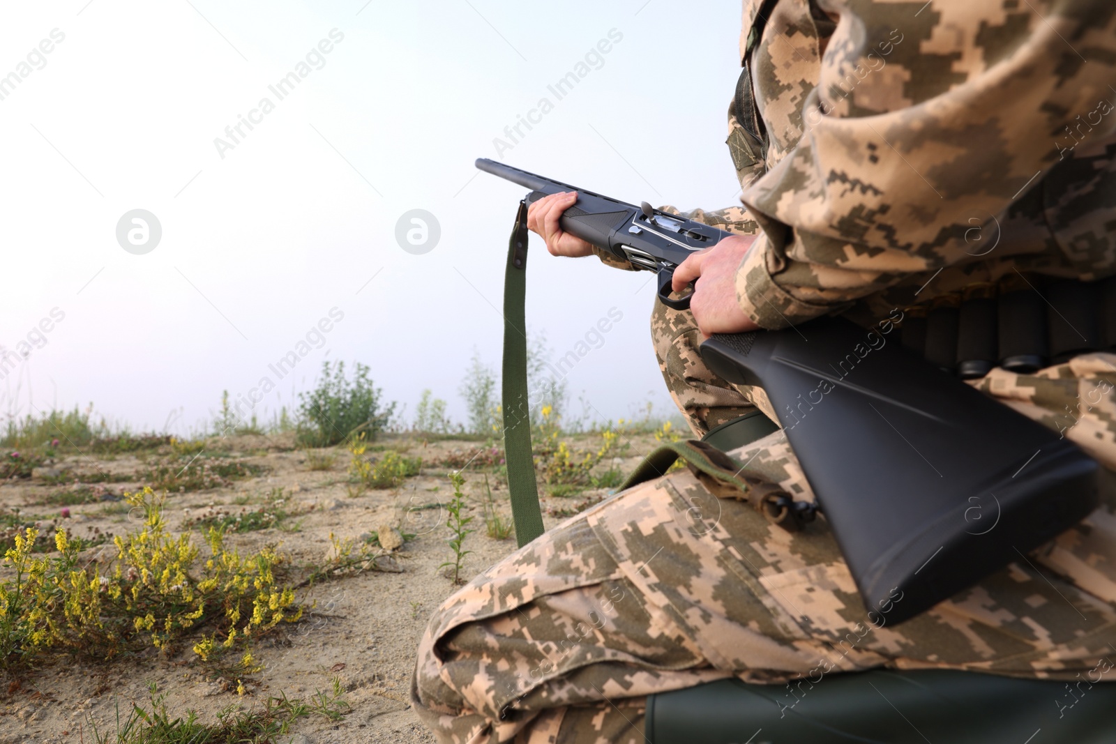 Photo of Man wearing camouflage with hunting rifle outdoors, closeup. Space for text