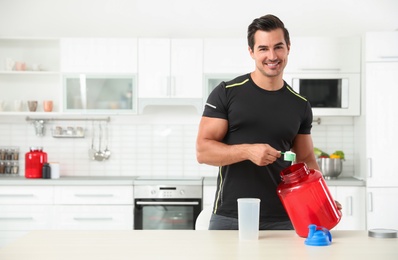 Photo of Young athletic man preparing protein shake in kitchen, space for text