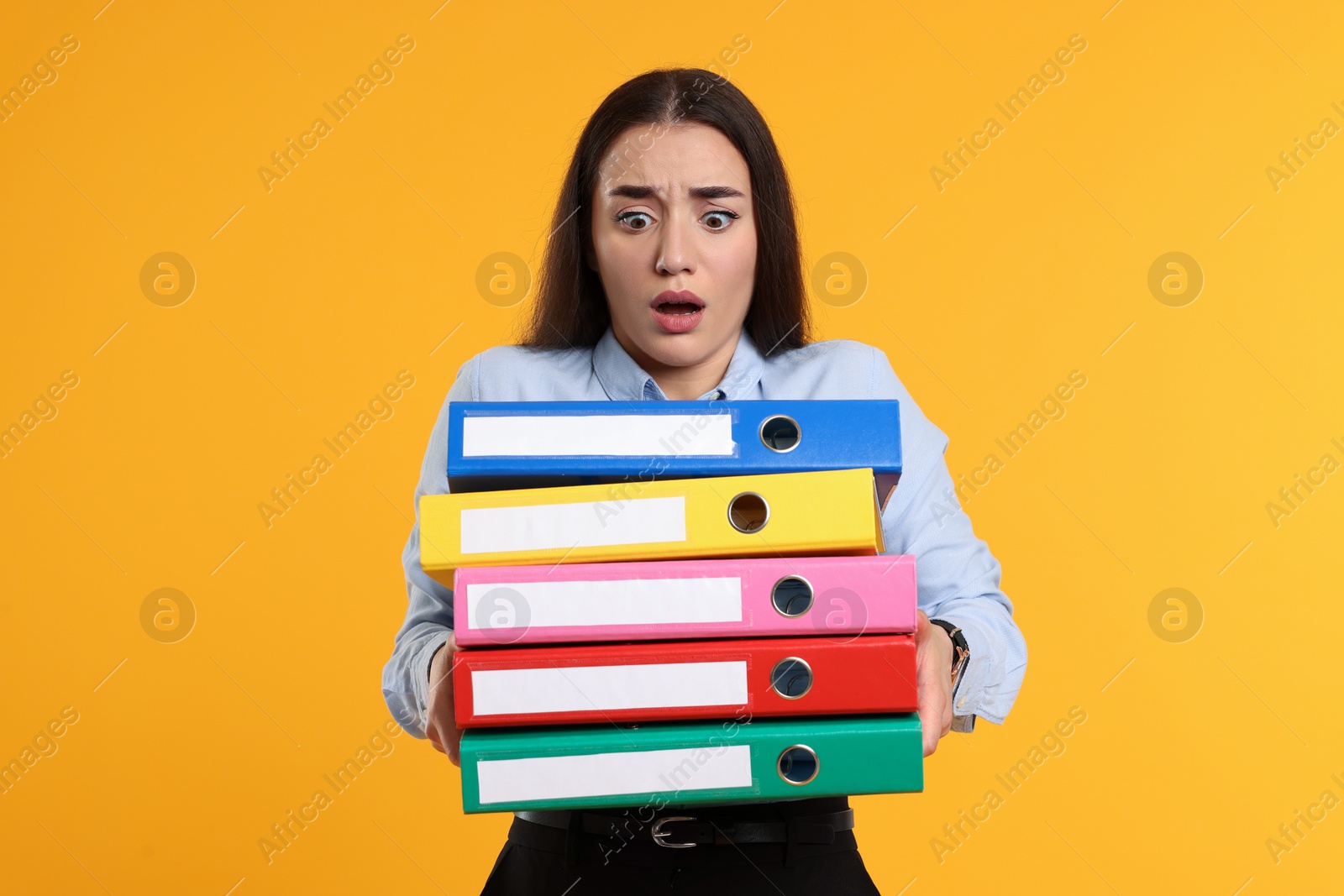 Photo of Shocked woman with folders on orange background