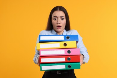 Photo of Shocked woman with folders on orange background