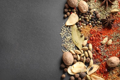 Photo of Different aromatic spices on dark background, top view with space for text
