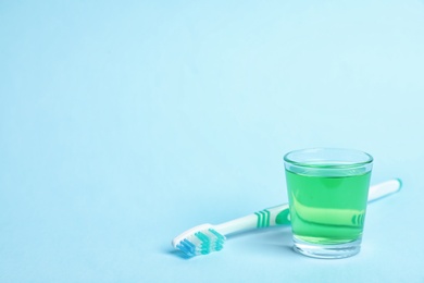 Photo of Glass with mouthwash, toothbrush and space for text on color background. Teeth hygiene