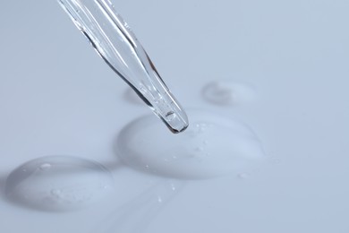 Glass pipette and transparent liquid on white background, closeup