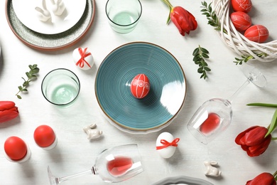 Festive Easter table setting with painted eggs on wooden background, flat lay