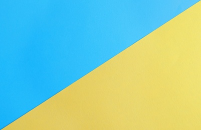 Photo of Blue and yellow paper sheets as colorful background, top view