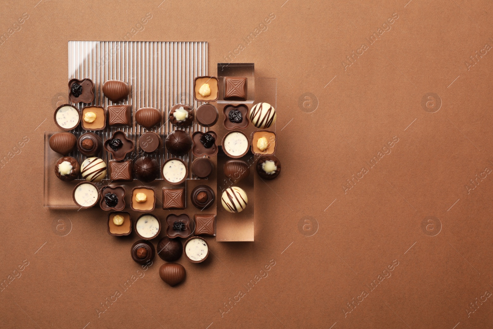 Photo of Heart made with delicious chocolate candies on brown background, top view. Space for text