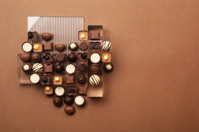 Photo of Heart made with delicious chocolate candies on brown background, top view. Space for text