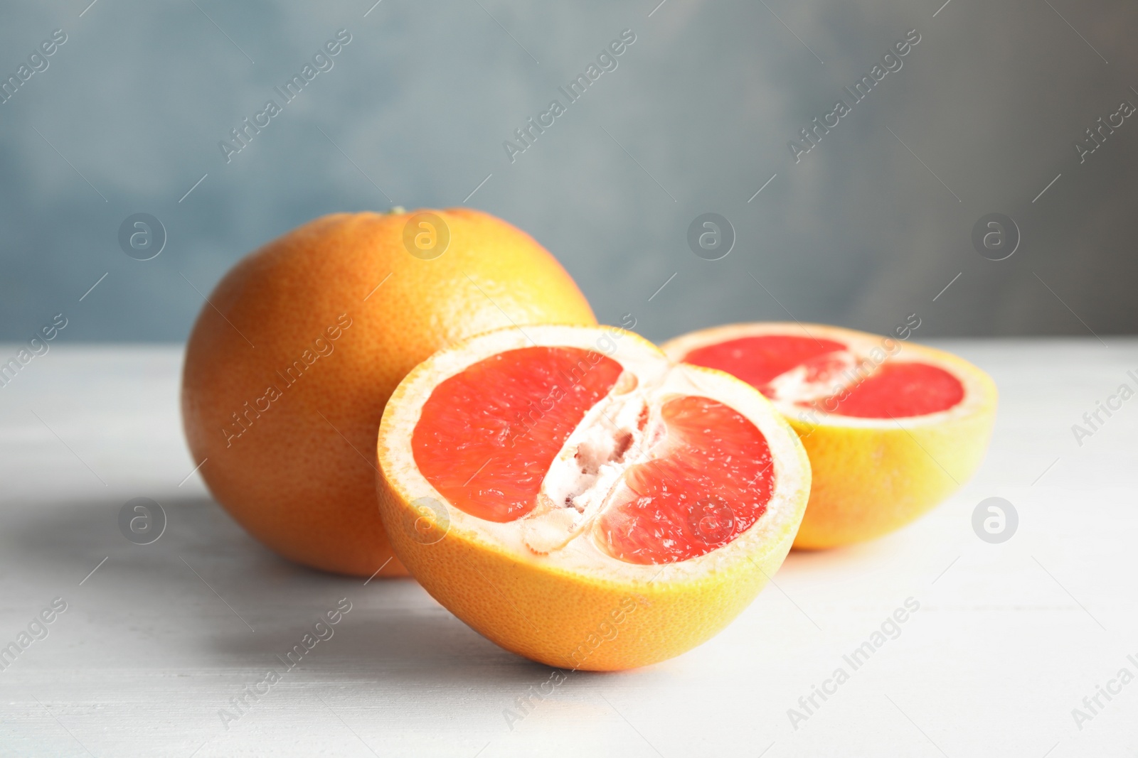 Photo of Whole and sliced tasty grapefruits on wooden table