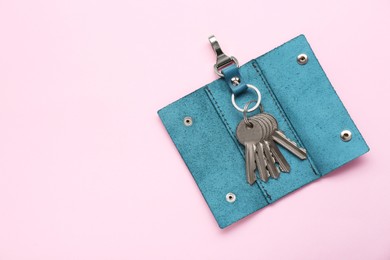 Photo of Leather ring holder with keys on pink background, top view. Space for text