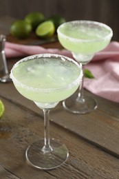 Delicious Margarita cocktail in glasses on wooden table, closeup