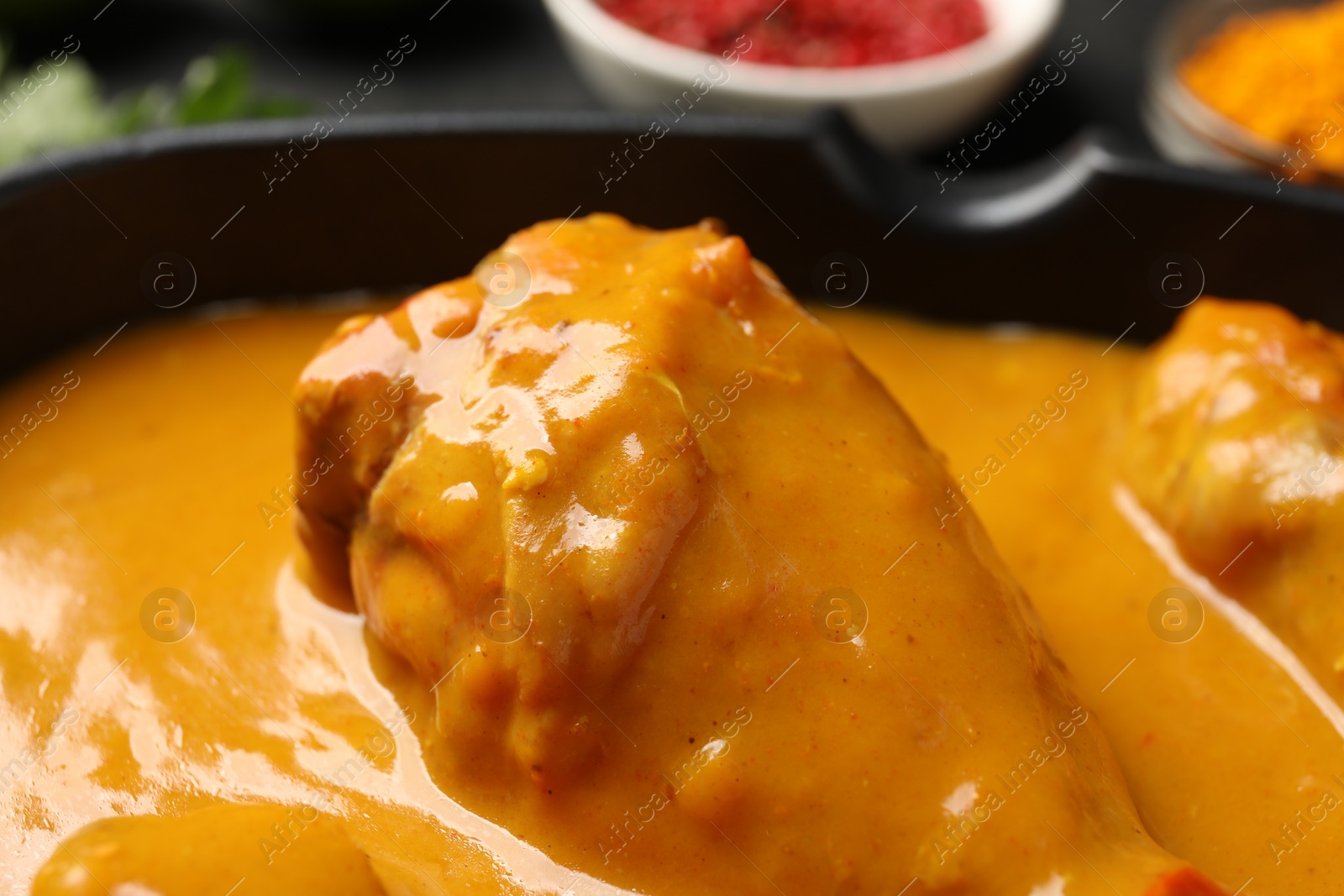 Photo of Tasty chicken curry in black frying pan, closeup