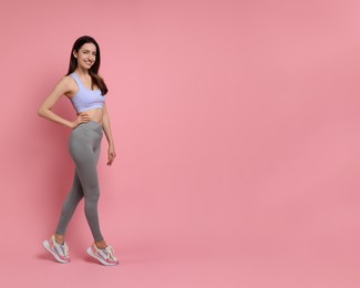 Happy young woman with slim body posing on pink background