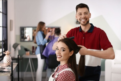 Professional hairdresser working with client in beauty salon