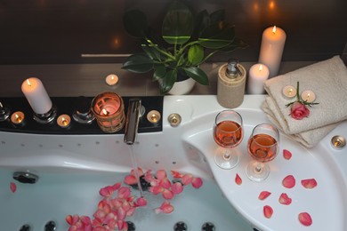 Photo of Bathtub with glasses of wine and candles indoors, above view. Romantic atmosphere