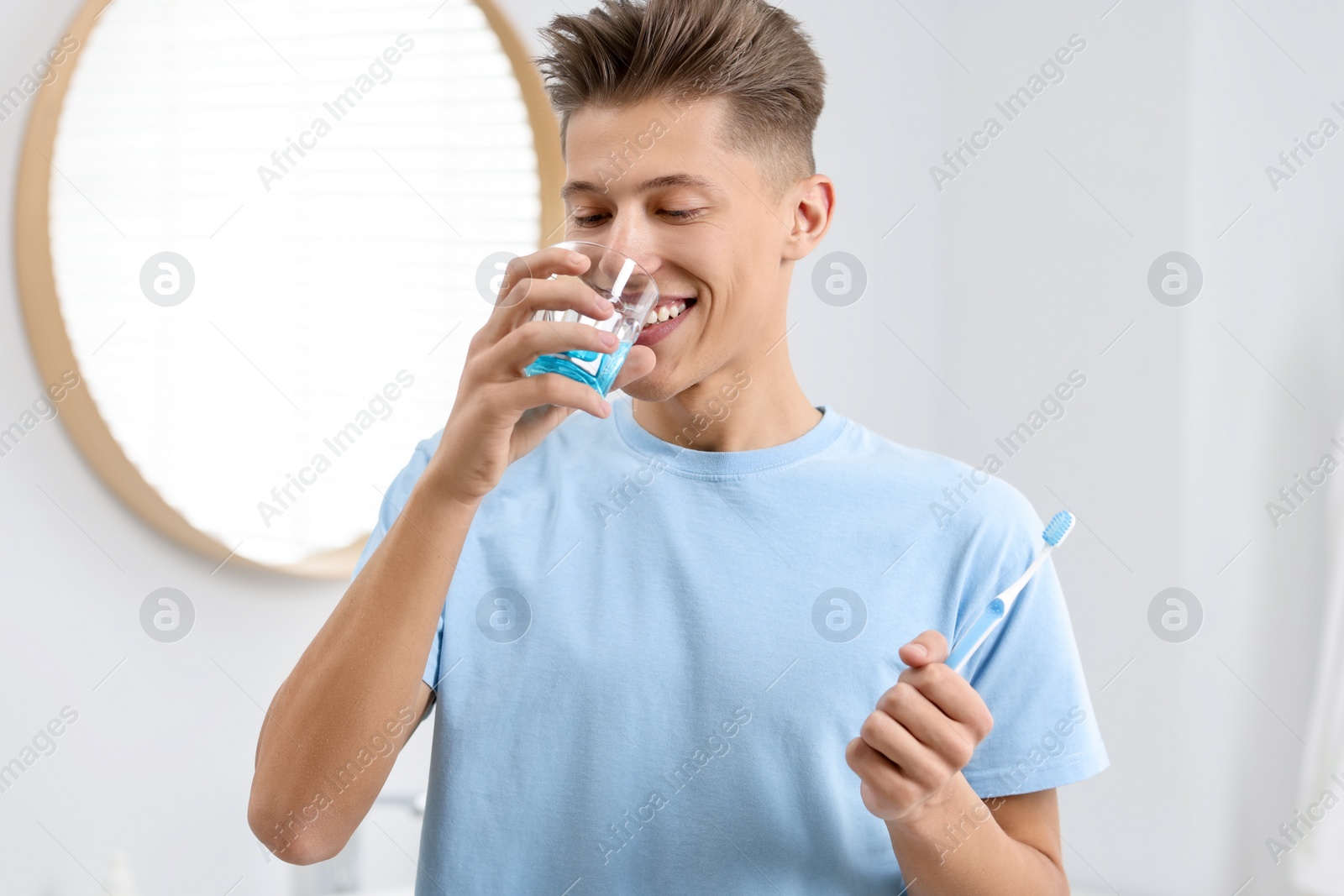 Photo of Young man using mouthwash in bathroom. Oral hygiene