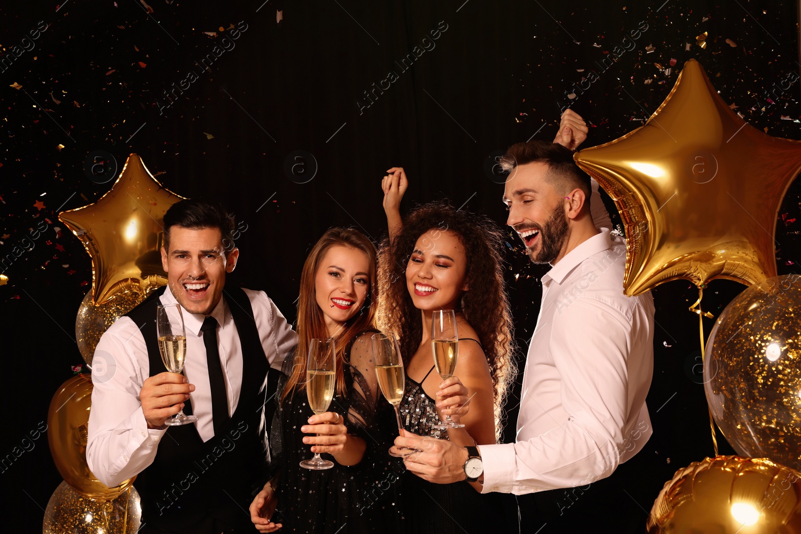 Photo of Happy friends with glasses of sparkling wine celebrating New Year on black background