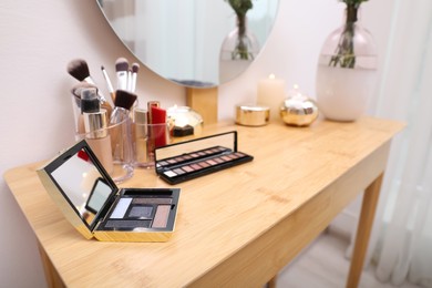 Photo of Different makeup products on wooden dressing table indoors