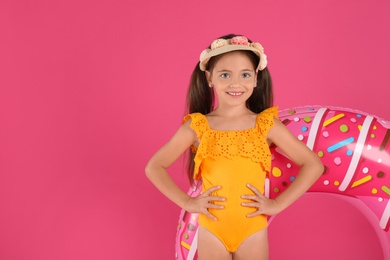 Photo of Cute little child in beachwear with bright inflatable ring on pink background. Space for text