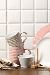 Beautiful ceramic dishware, cups and cutlery on wooden table