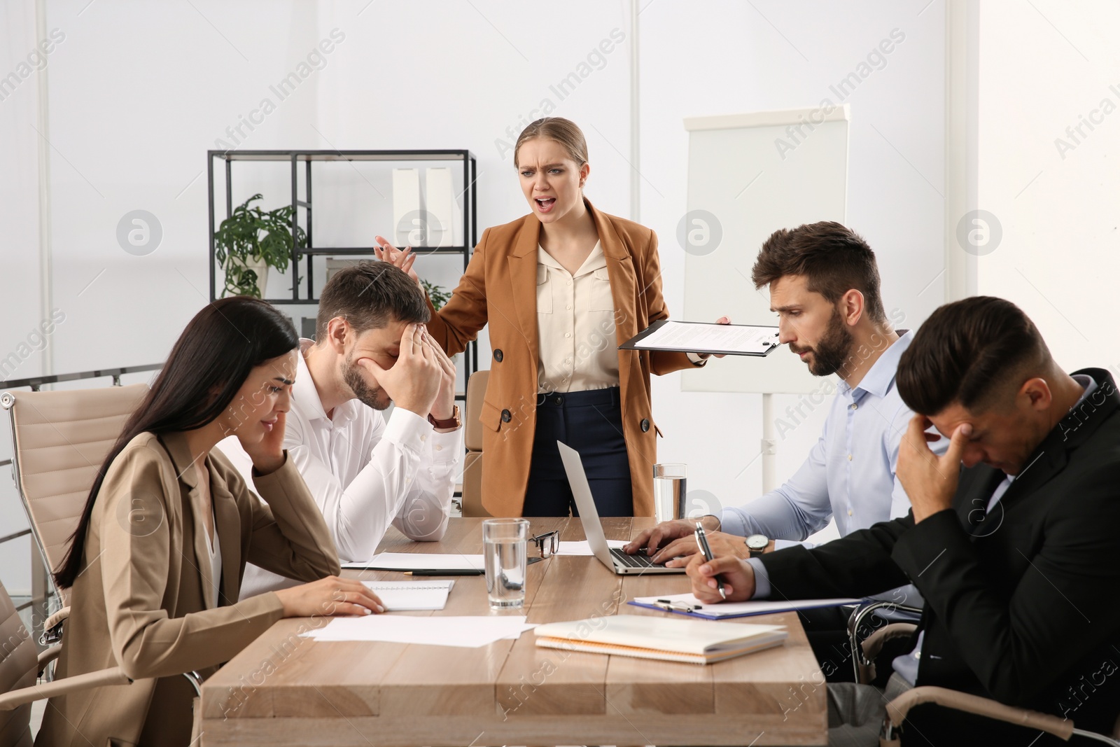 Photo of Boss screaming at employees in office. Toxic work environment