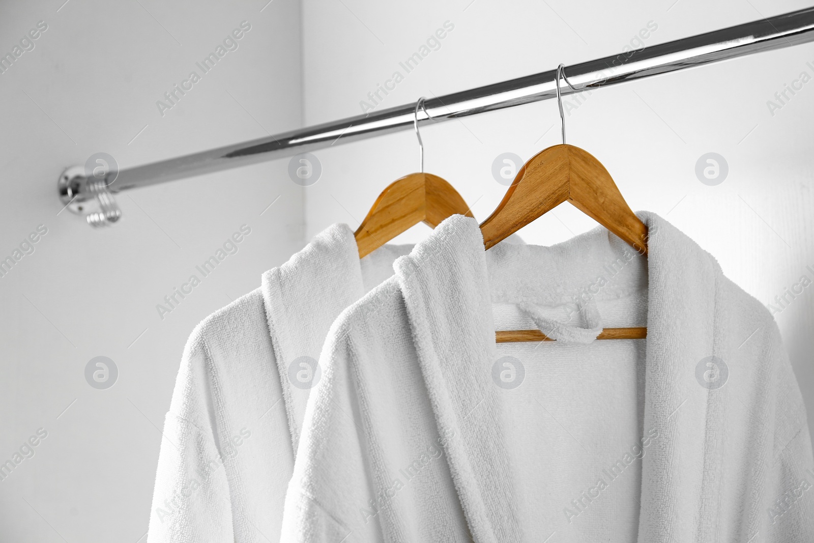 Photo of Soft comfortable bathrobes hanging on rack in closet