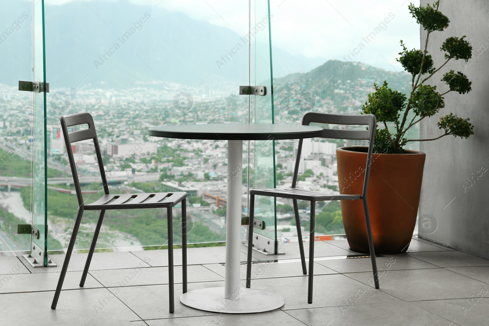 Photo of Coffee table and chairs against picturesque landscape of city in cafe