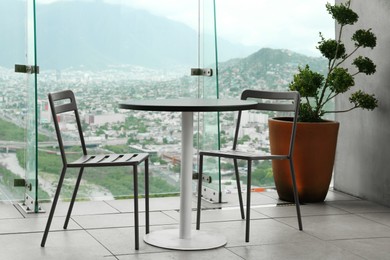 Coffee table and chairs against picturesque landscape of city in cafe