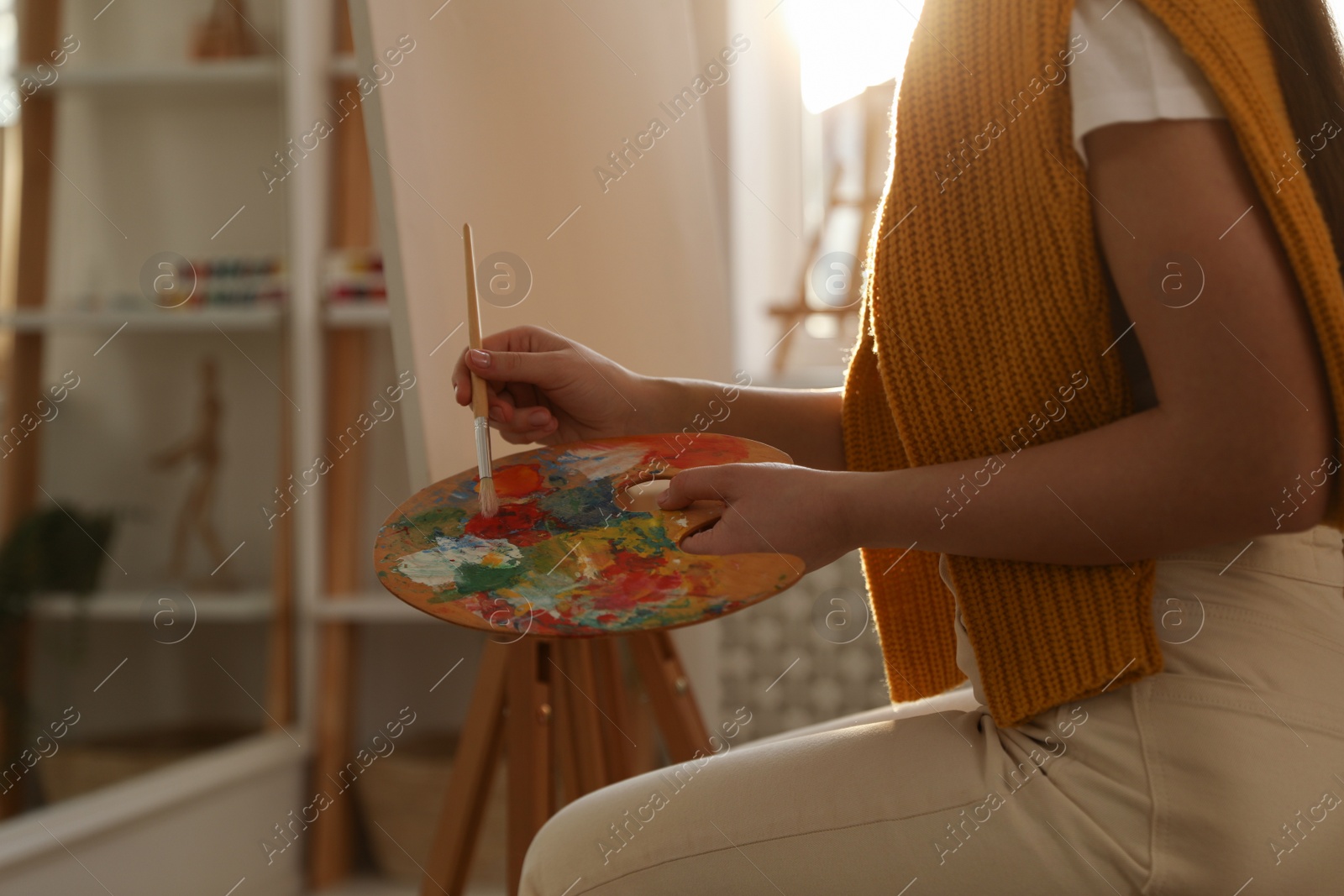 Photo of Young woman drawing on easel at home, closeup