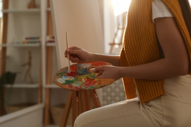 Photo of Young woman drawing on easel at home, closeup