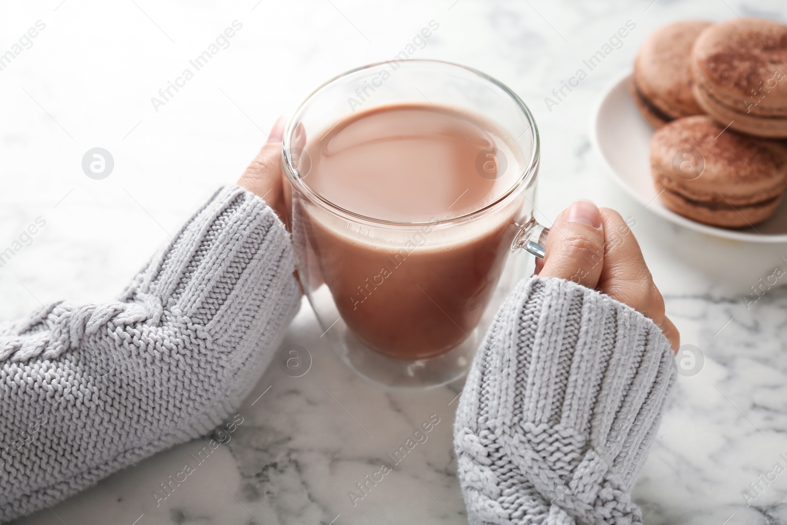 Photo of Young woman with delicious hot cocoa drink at table, closeup