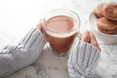 Photo of Young woman with delicious hot cocoa drink at table, closeup