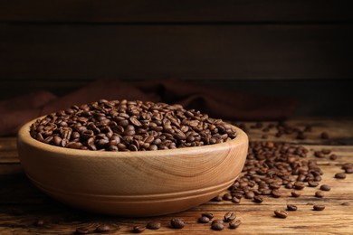 Bowl of roasted coffee beans on wooden table. Space for text