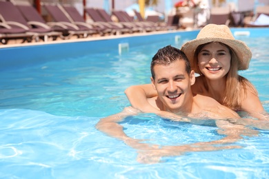 Happy couple relaxing in blue swimming pool outdoors