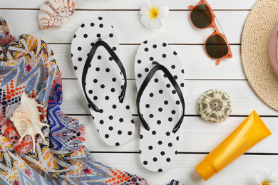 Flat lay composition with flip flops and beach accessories on white wooden background