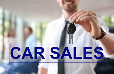Salesman with keys in car dealership, closeup