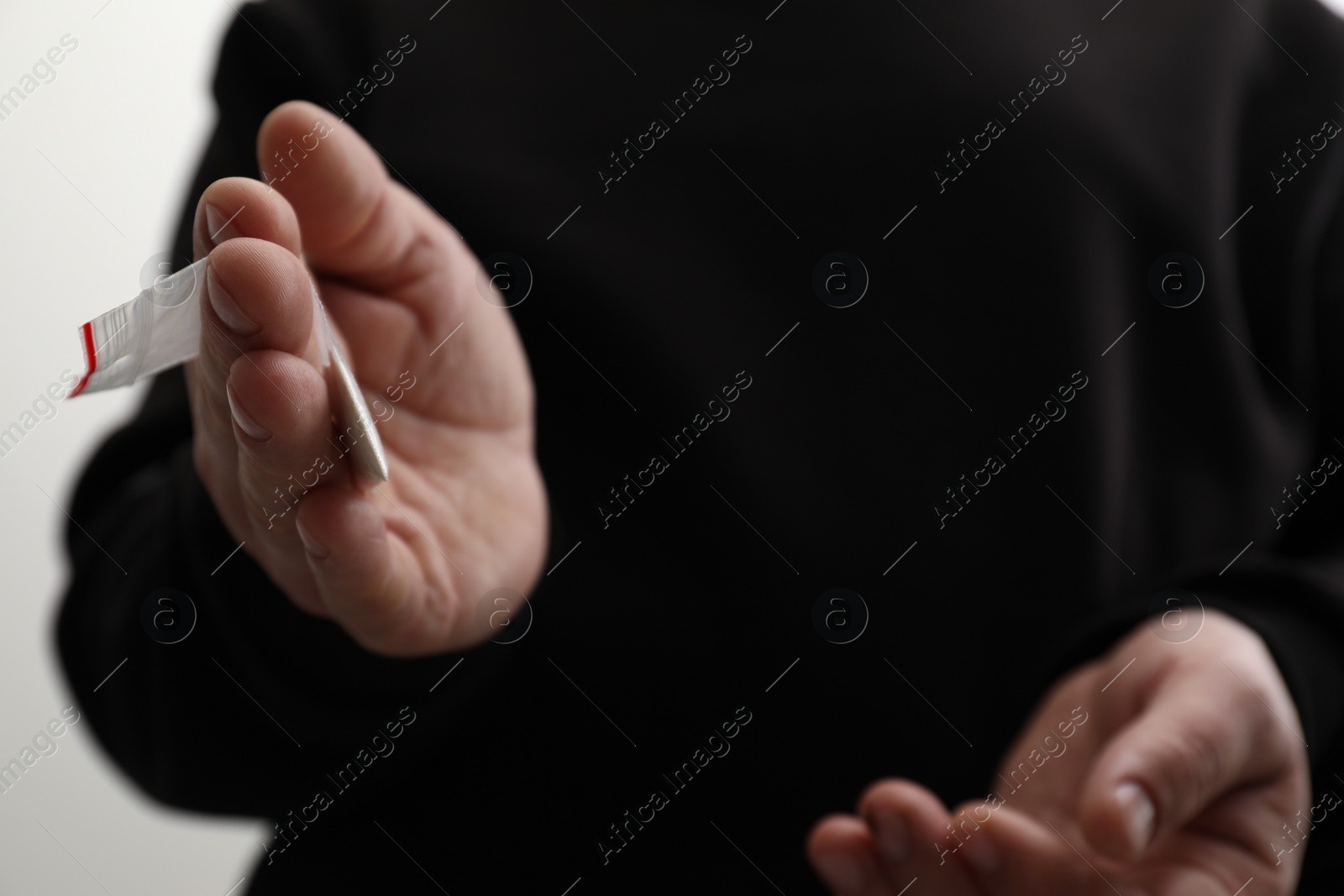 Photo of Drug addiction. Man with plastic bag of cocaine on light background, closeup