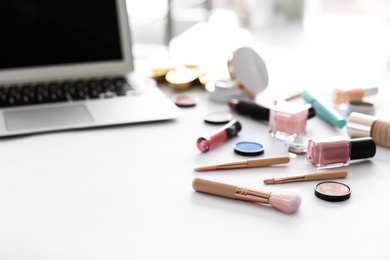 Makeup products for woman and laptop on table