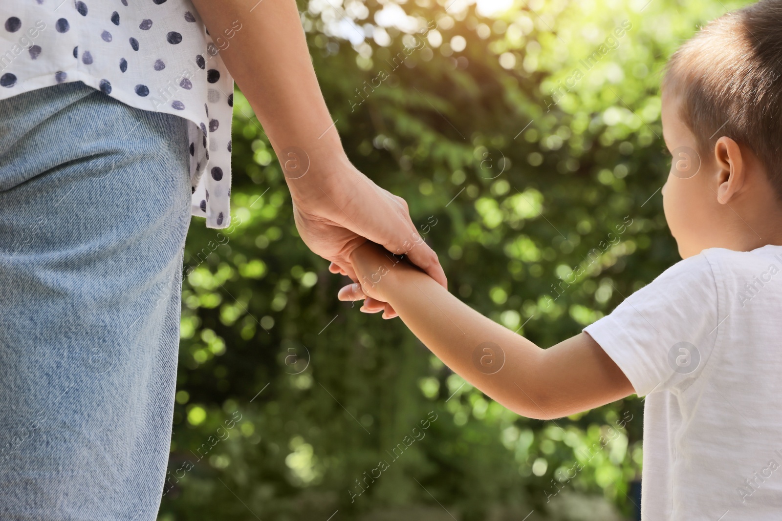 Photo of Mom and her child holding hands in park, closeup