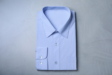 Stylish light blue shirt on grey background, top view. Dry-cleaning service