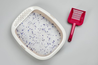 Cat litter tray with filler and scoop on light background, flat lay