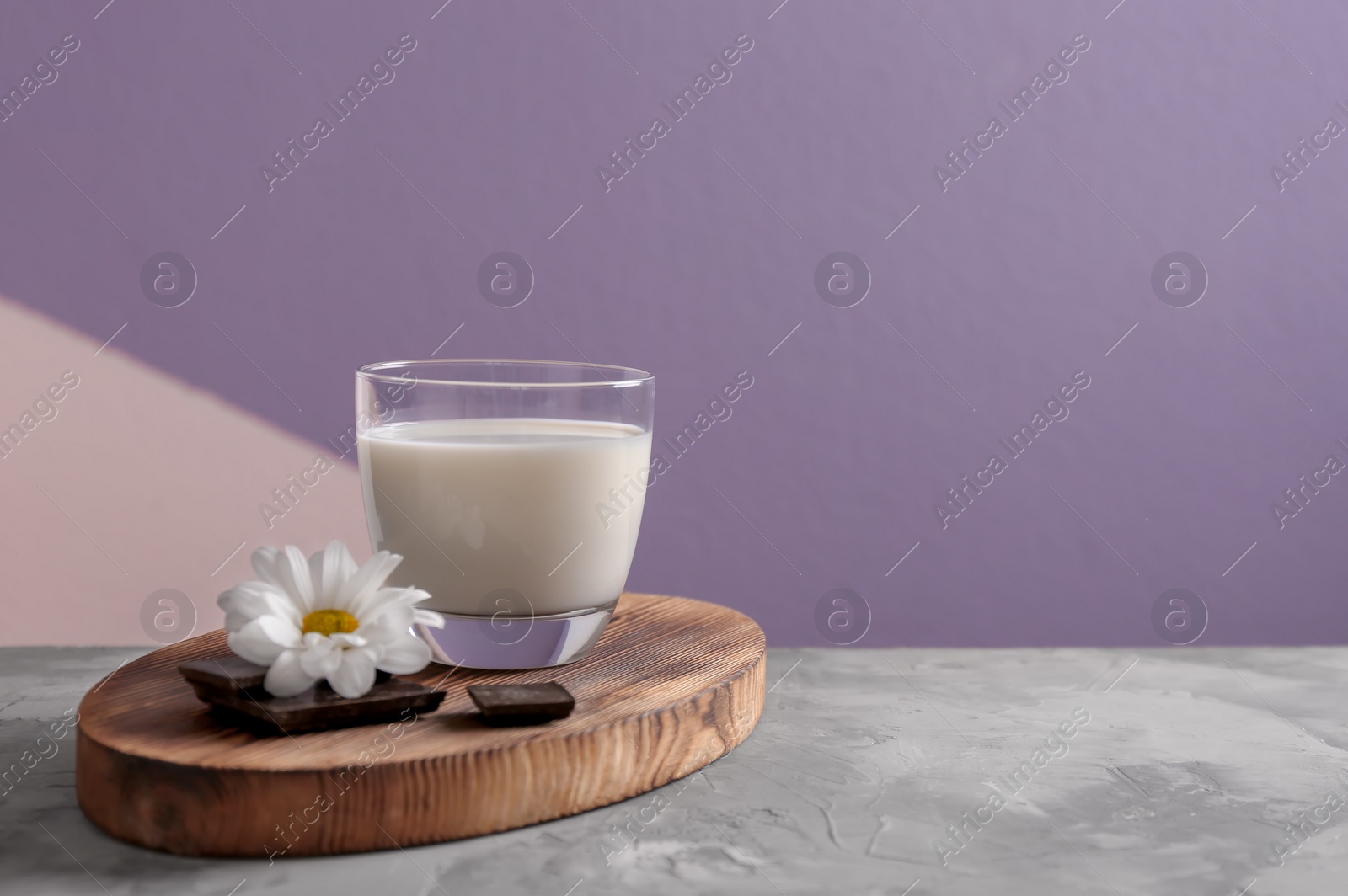 Photo of Glass of milk and chocolate on table against color background