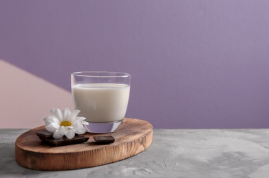 Photo of Glass of milk and chocolate on table against color background