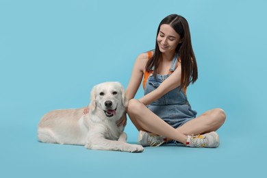 Photo of Happy woman with cute Labrador Retriever dog on light blue background. Adorable pet