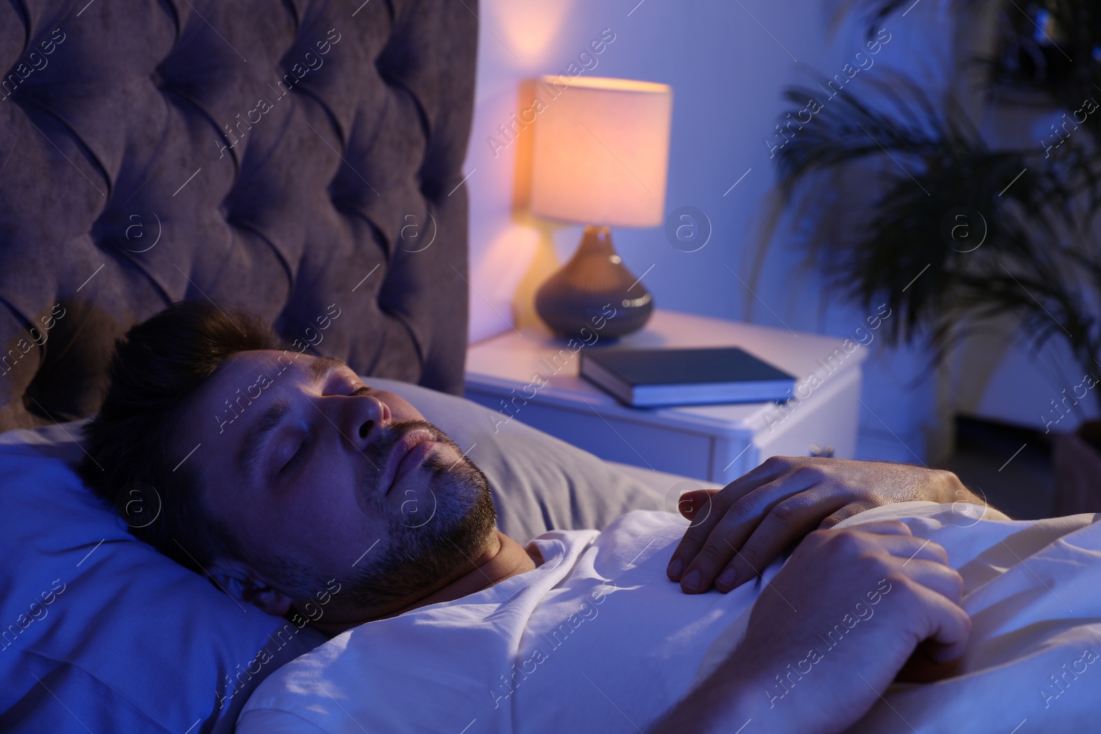 Photo of Handsome man sleeping on pillow in dark room at night. Bedtime